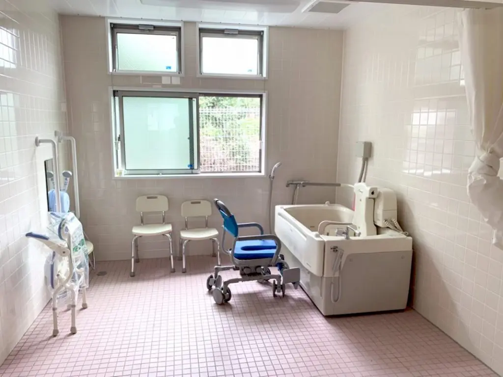 介護用浴室。大型浴槽、シャワーチェア、手すり、入浴補助設備が完備されている。